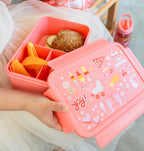 bento lunchbox in handjes van kind, gevuld met broodje en fruit