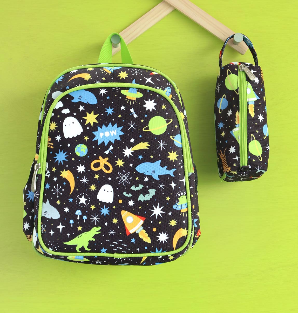 Vooraanzicht van zwarte galaxy rugzak met bijpassend etui met stoere print, op groene achtergrond