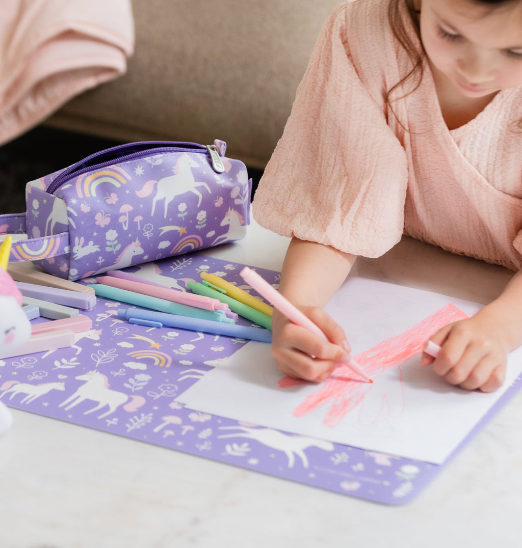 paarse placemat en etui met eenhoorn print en meisje die tekening maakt